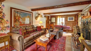 A cozy log cabin interior with a leather sofa, a rocking horse, and a mounted deer head. - Award-winning Log Cabin, Top 5 in New England! (Londonderry)