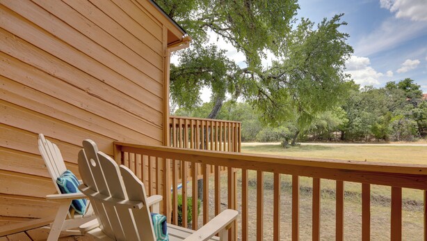 A wooden deck with a rocking chair and a view of a grassy area with trees. - Wimberley Retreat w/ Grill < 2 Mi to Jacob's Well! (Wimberley)