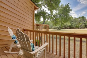 A wooden deck with a rocking chair and a view of a grassy area with trees. - Wimberley Retreat w/ Grill < 2 Mi to Jacob's Well! (Wimberley)