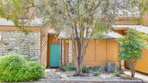 A building with a stone facade, a wooden door, and a small garden area with plants and a tree. - Wimberley Retreat w/ Grill < 2 Mi to Jacob's Well! (Wimberley)