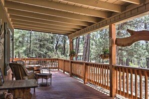 A wooden deck with wicker furniture and a view of a forest. - 'hilda's Cabin' Mtn-view Retreat in Pine! (Pine)