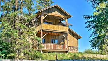 A wooden cabin with a balcony, surrounded by trees.