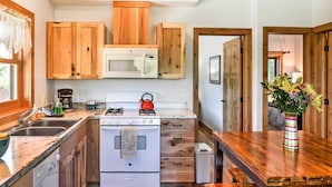 Een keuken met houten kastjes, een magnetron, een fornuis en een spoelbak.