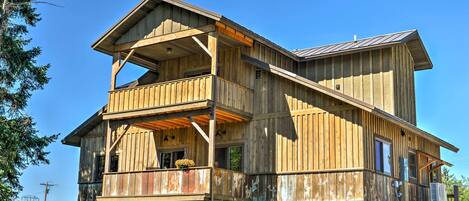 A rustic wooden cabin with a balcony, a second-story deck, and a sloped roof.
