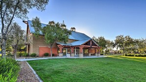 A building with a red brick facade, a blue metal roof, and a covered porch area. - Heated Pool + Putting Green: Luxe Gilbert Home (Gilbert)