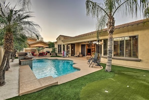 A backyard with a swimming pool, palm trees, and a patio area with outdoor furniture. - Heated Pool + Putting Green: Luxe Gilbert Home (Gilbert)