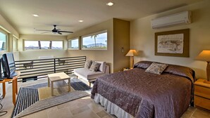 A bedroom with a large bed, a desk with a computer, a sofa, and a balcony with a view of the mountains. - Cozy Casita w/ Mtn View + Pool & Hot Tub Access (Carefree)