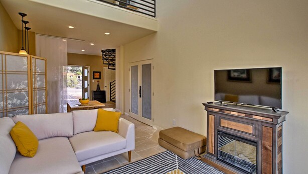 A spacious living area with a white sofa, a fireplace, and a balcony. - Cozy Casita w/ Mtn View + Pool & Hot Tub Access (Carefree)