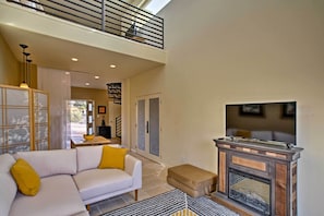 A spacious living area with a white sofa, a fireplace, and a balcony. - Cozy Casita w/ Mtn View + Pool & Hot Tub Access (Carefree)