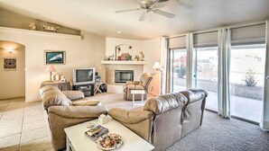 A living room with a fireplace, leather sofas, a television, and a ceiling fan.