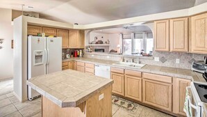 A modern kitchen with wooden cabinets, a built-in dishwasher, and a large island.