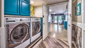 A laundry area with two front-loading washing machines, a teal cabinet, and a hallway leading to a kitchen area. - Mammoth Cave Rental on 50 Acres: Shared Amenities (Mammoth Cave)