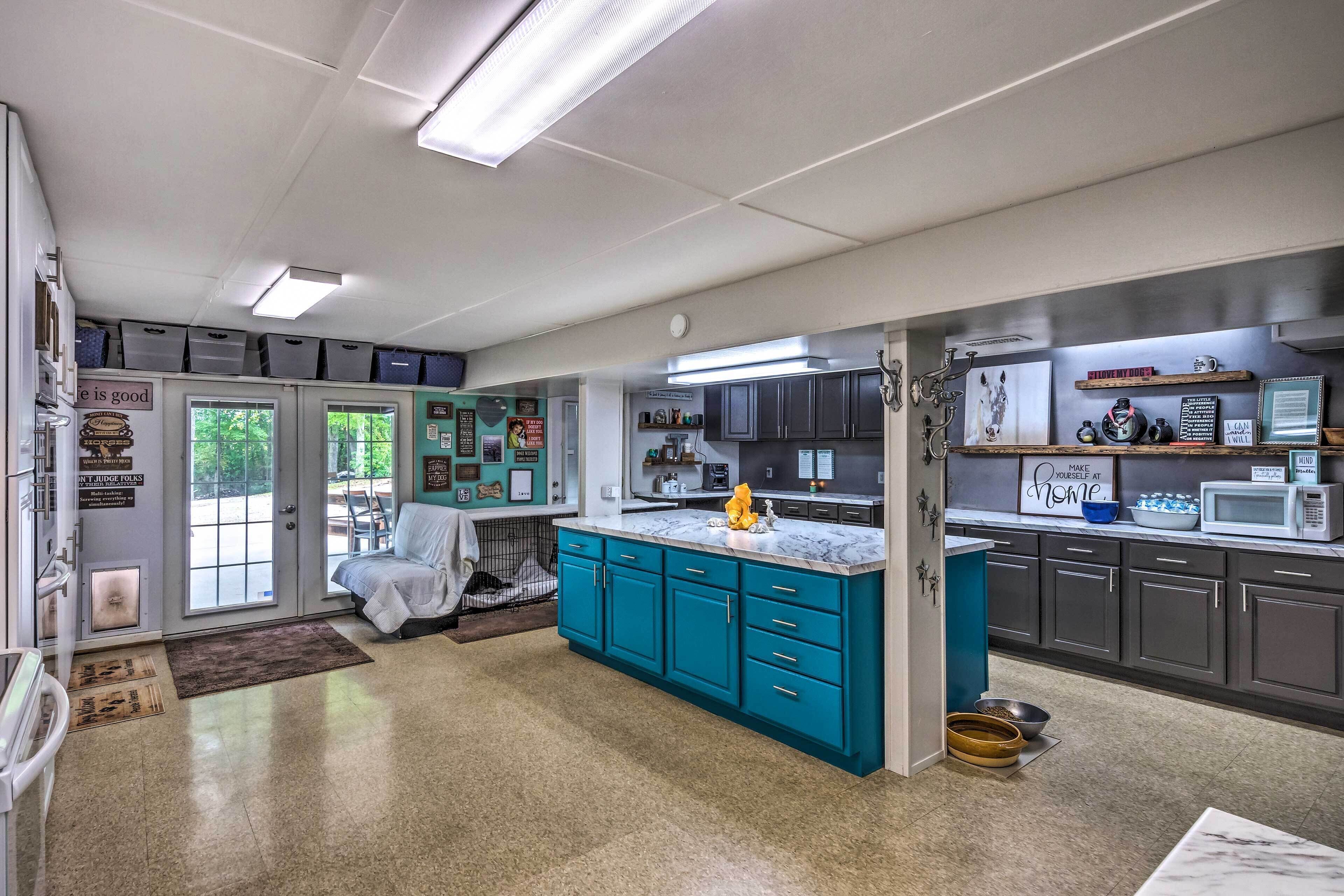 A kitchen with teal cabinets, a marble countertop, and a dog bed in the corner.