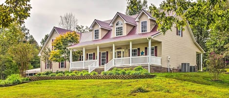 Een groot, tweelaags huis met een veranda rondom en een verzorgd gazon.