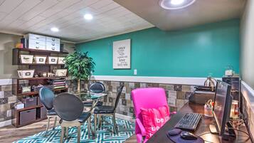 A modern office space with teal walls, a glass desk, and a bright ceiling.