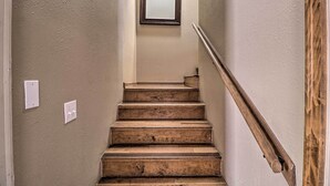 Eine Holztreppe mit Handlauf, Lichtschalter und einem Spiegel an der Wand.