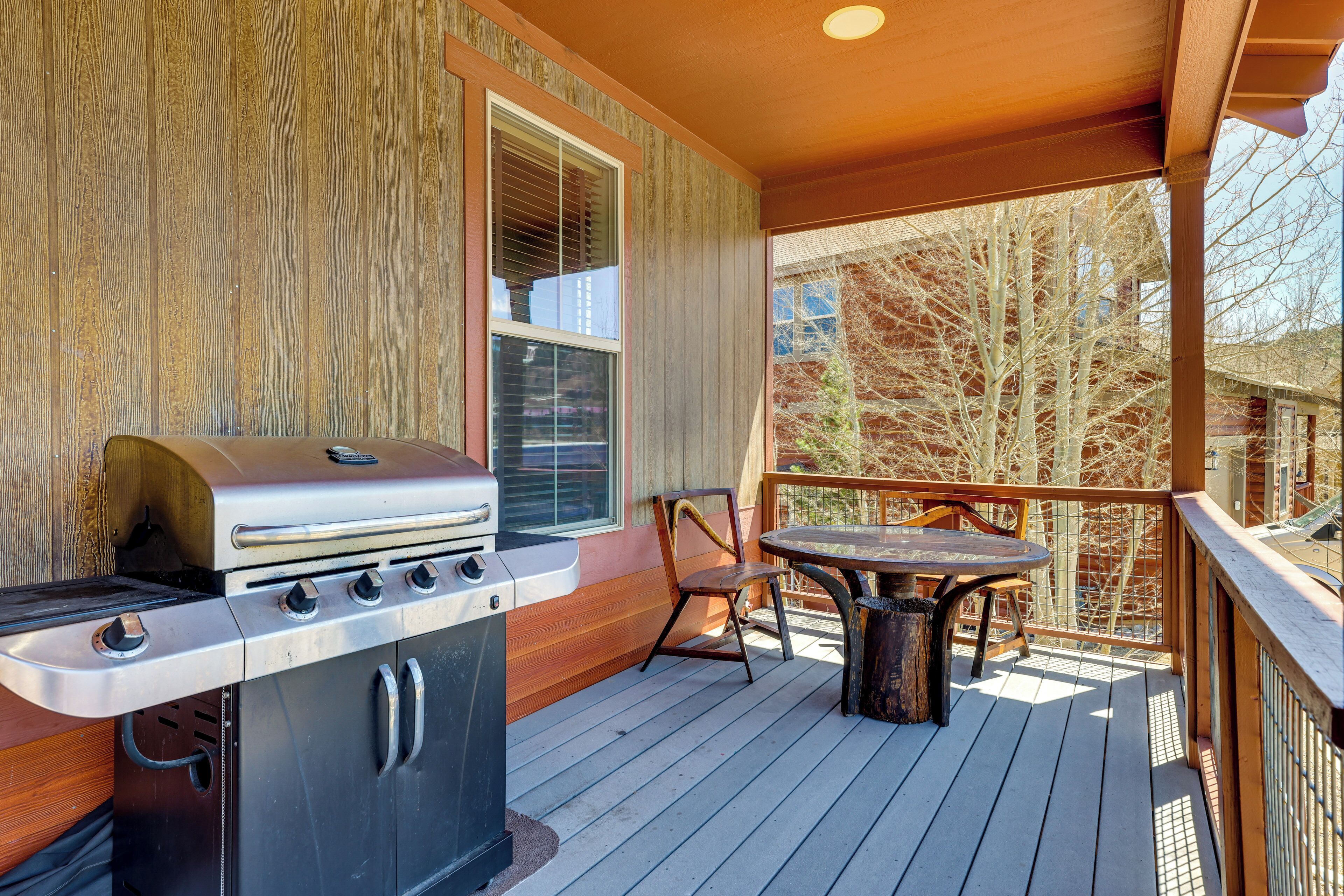 An outdoor deck with a grill, a table, and chairs.