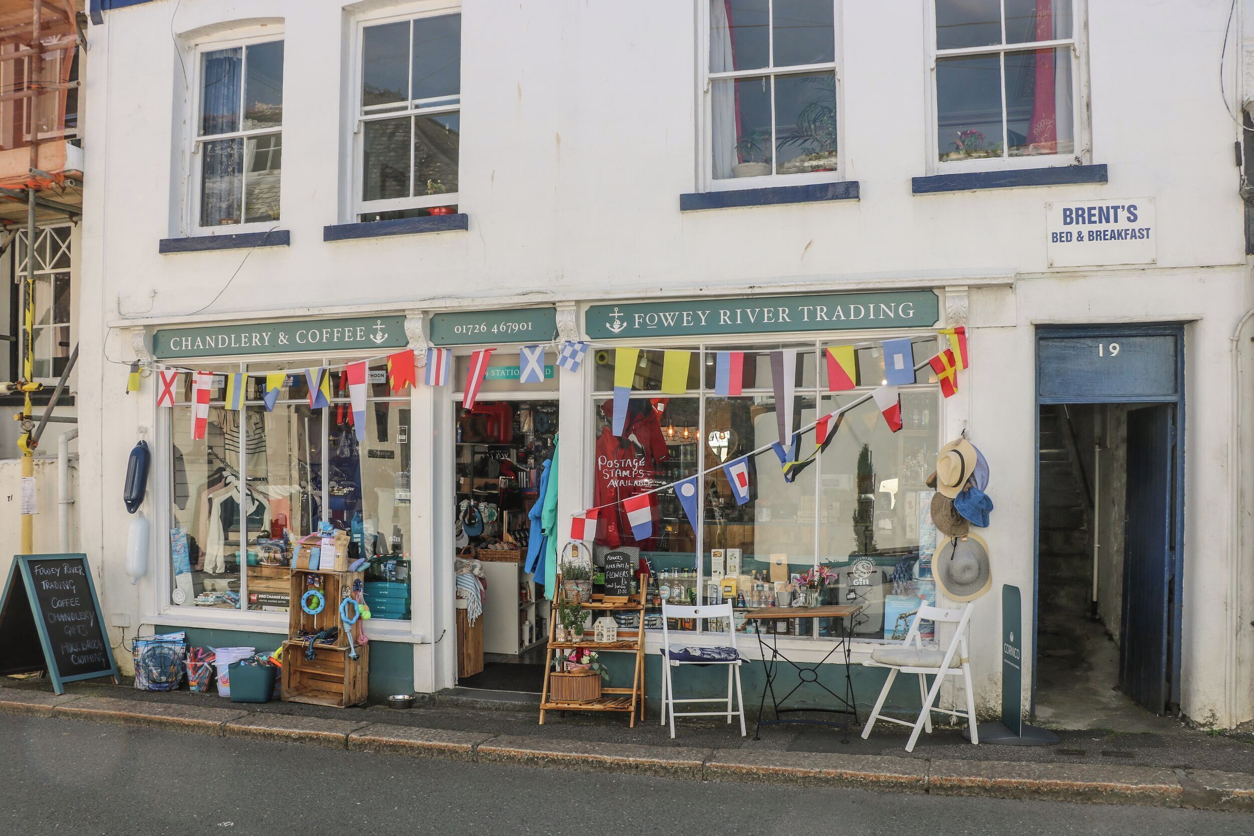 Une devanture de magasin avec une enseigne indiquant « Fowey River Trading » et « Articles de marine et café ».