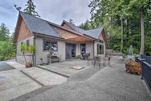 A two-story house with a covered patio, outdoor seating, and a stone fireplace.