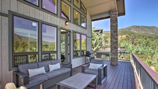 A deck with outdoor furniture, large windows, and a stone pillar. - Mountain View Modern Cabin: Luxury Pine Home! (Pine)