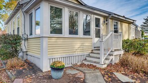 A single-story house with a front porch, large windows, and a small front yard with a potted plant. - < 1 Mi to Beach! Kennebunk Cottage w/ Yard (Kennebunk)