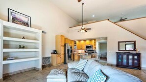 A modern living room with a grey sofa, a white entertainment unit, and a kitchen in the background. - Pool & Putting Green: Pet-friendly Glendale Home (Glendale)