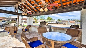 A covered outdoor patio with wicker furniture, a glass table, and a grill area. - Pool & Putting Green: Pet-friendly Glendale Home (Glendale)