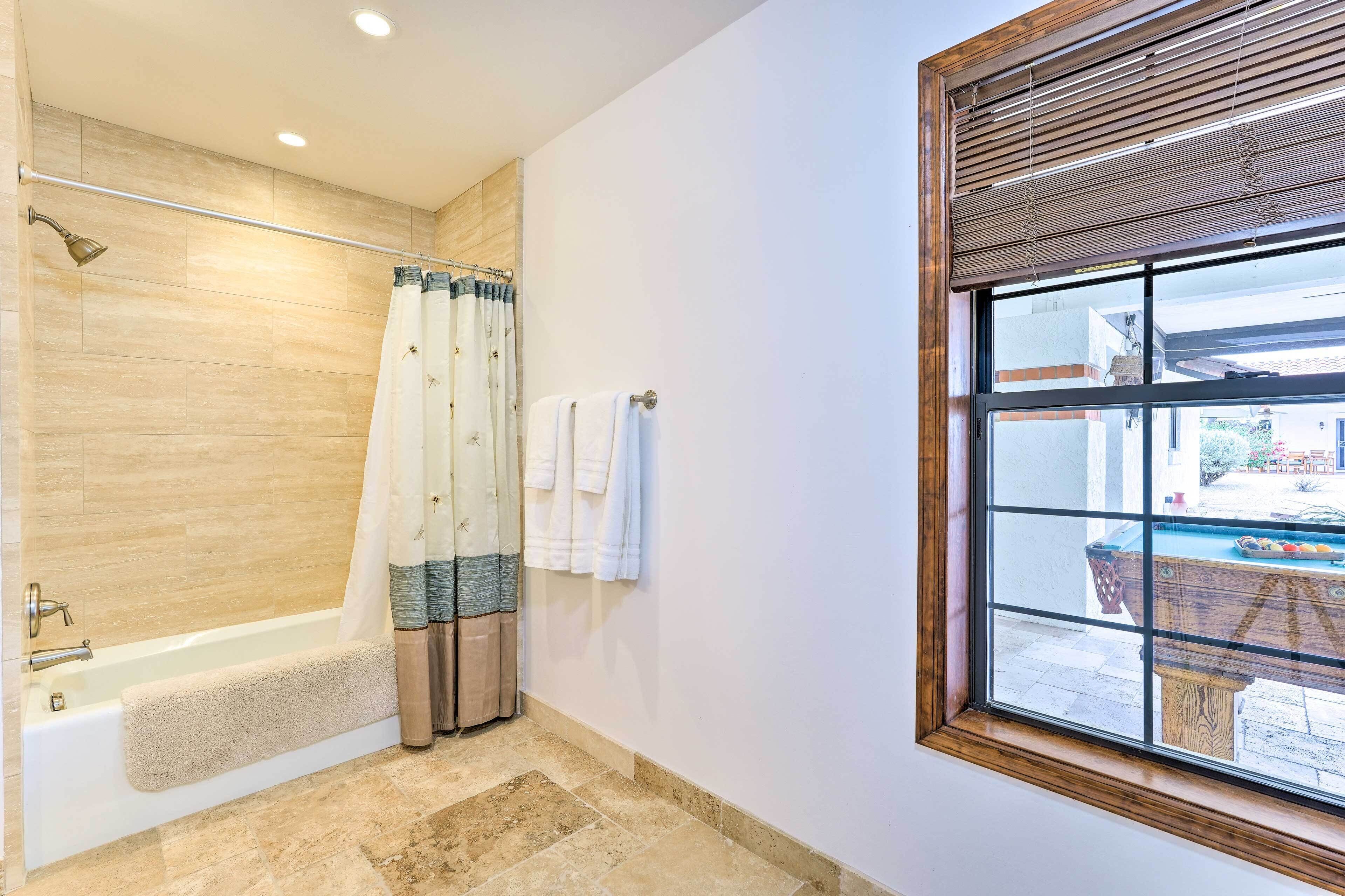 A bathroom with a bathtub, a shower curtain, and a window with blinds.