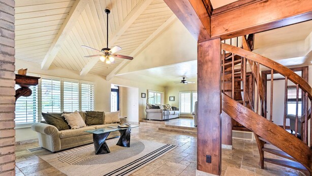 A spacious living area with a high ceiling, a wooden staircase, and a fireplace. - Pool & Putting Green: Pet-friendly Glendale Home (Glendale)