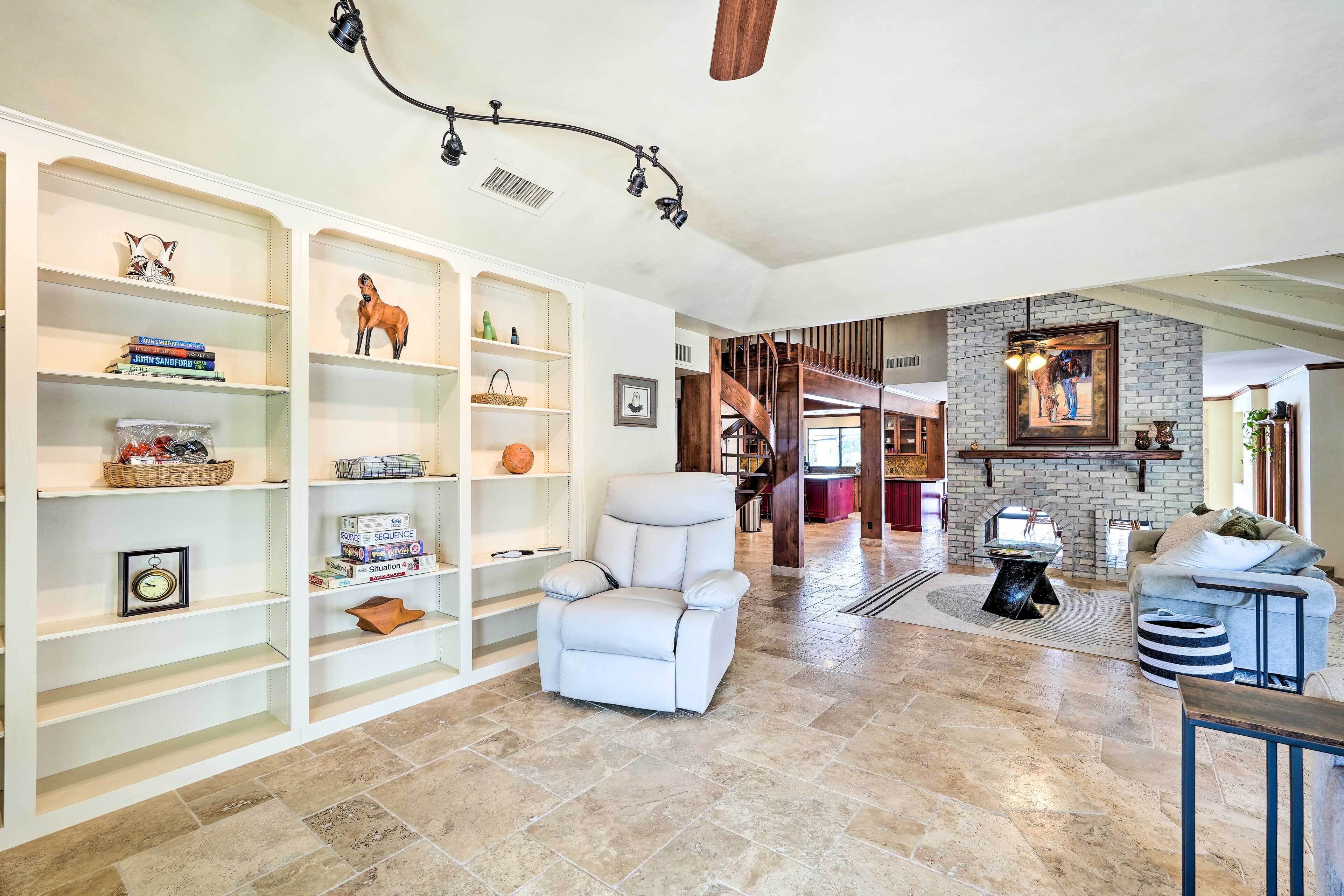 A spacious living room with a white leather sofa, a fireplace, and a staircase leading to another level.