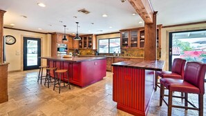 A spacious kitchen with a central island, wooden cabinets, and a large window providing a view of the outdoors. - Pool & Putting Green: Pet-friendly Glendale Home (Glendale)
