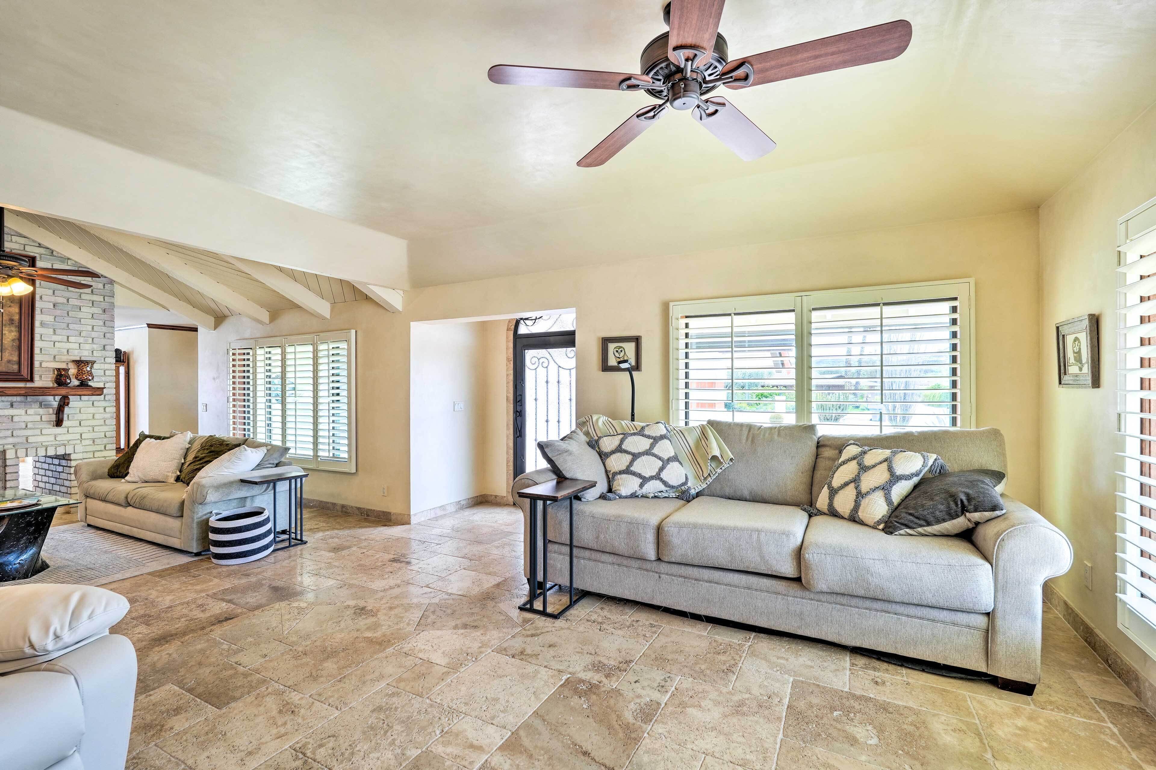 A spacious living room with a beige sofa, a coffee table, and a ceiling fan.