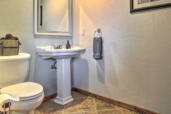 A bathroom with a toilet, sink, and mirror. - Stunning Mountain-view Ranch on 132 Acres! (Philipsburg)
