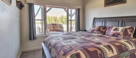 A bedroom with a large bed, a window with curtains, a wooden headboard, and a painting on the wall.