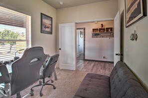 A room with a desk, office chair, and a couch. There is a door leading to another room with a mirror and shelves. - Near White Mountain Lake: Home w/ Balcony & Patio (Show Low)