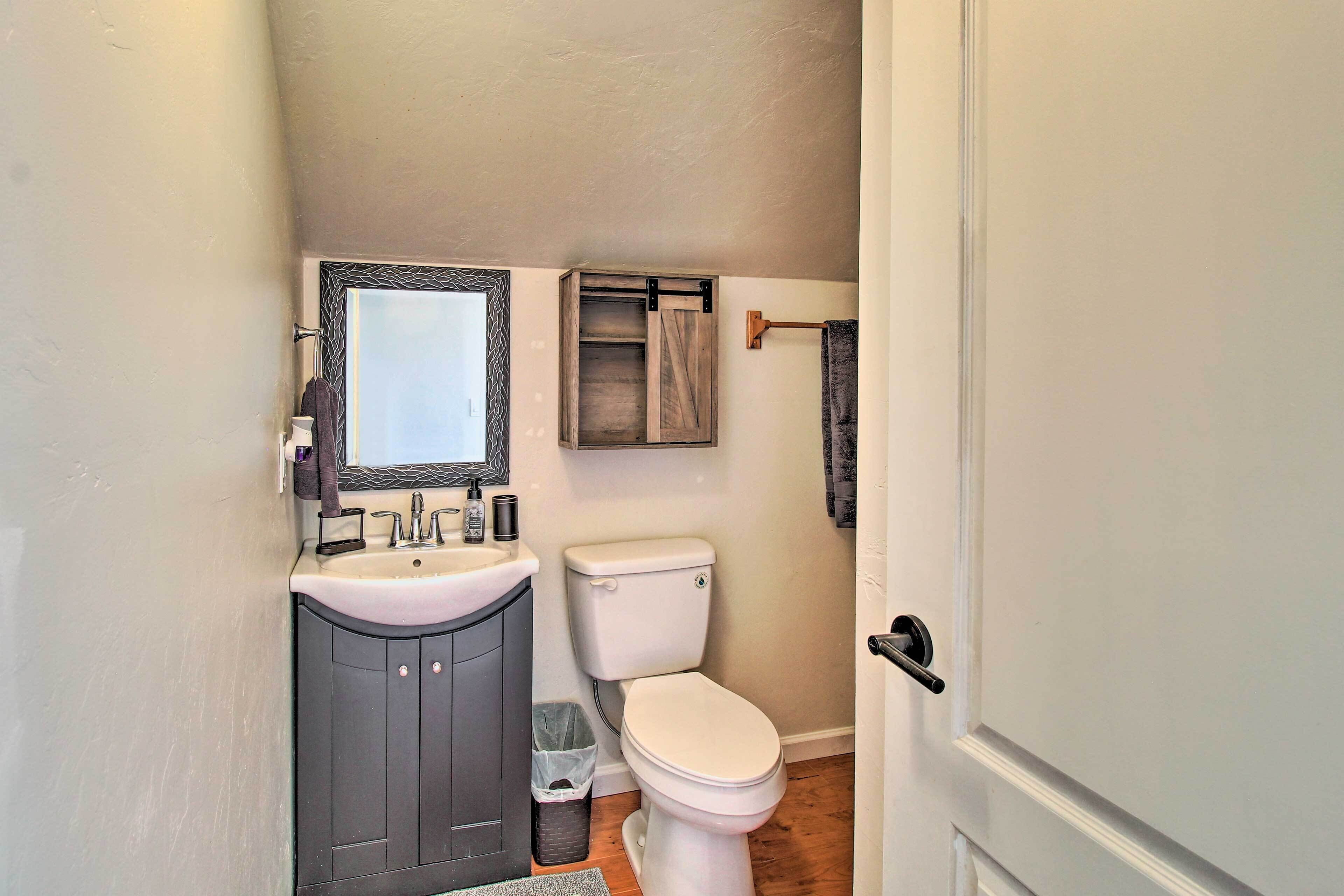 A bathroom with a sink, mirror, toilet, and towel rack.