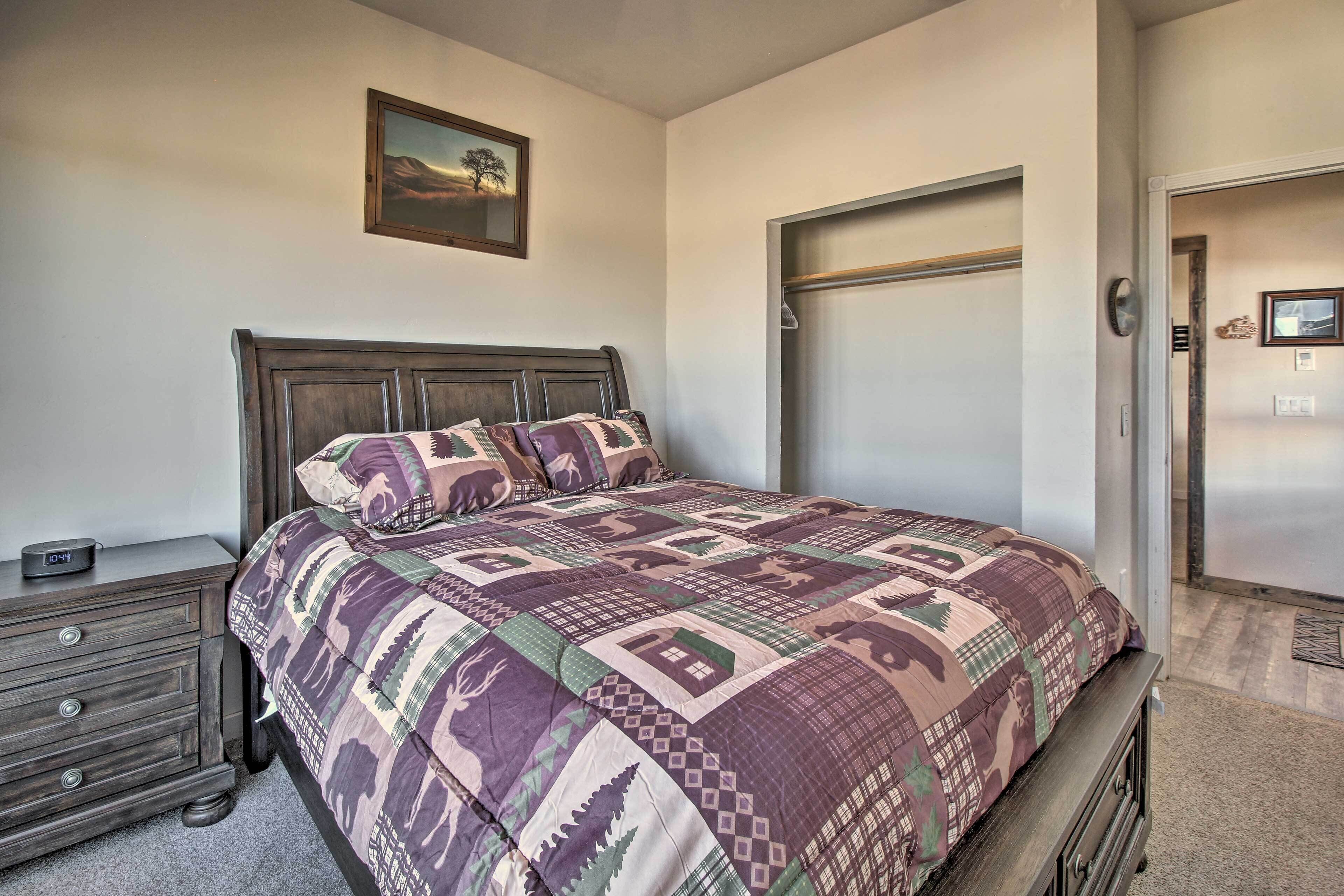 Une chambre à coucher avec un grand lit, une commode, une table de chevet, une porte et un tableau au mur.