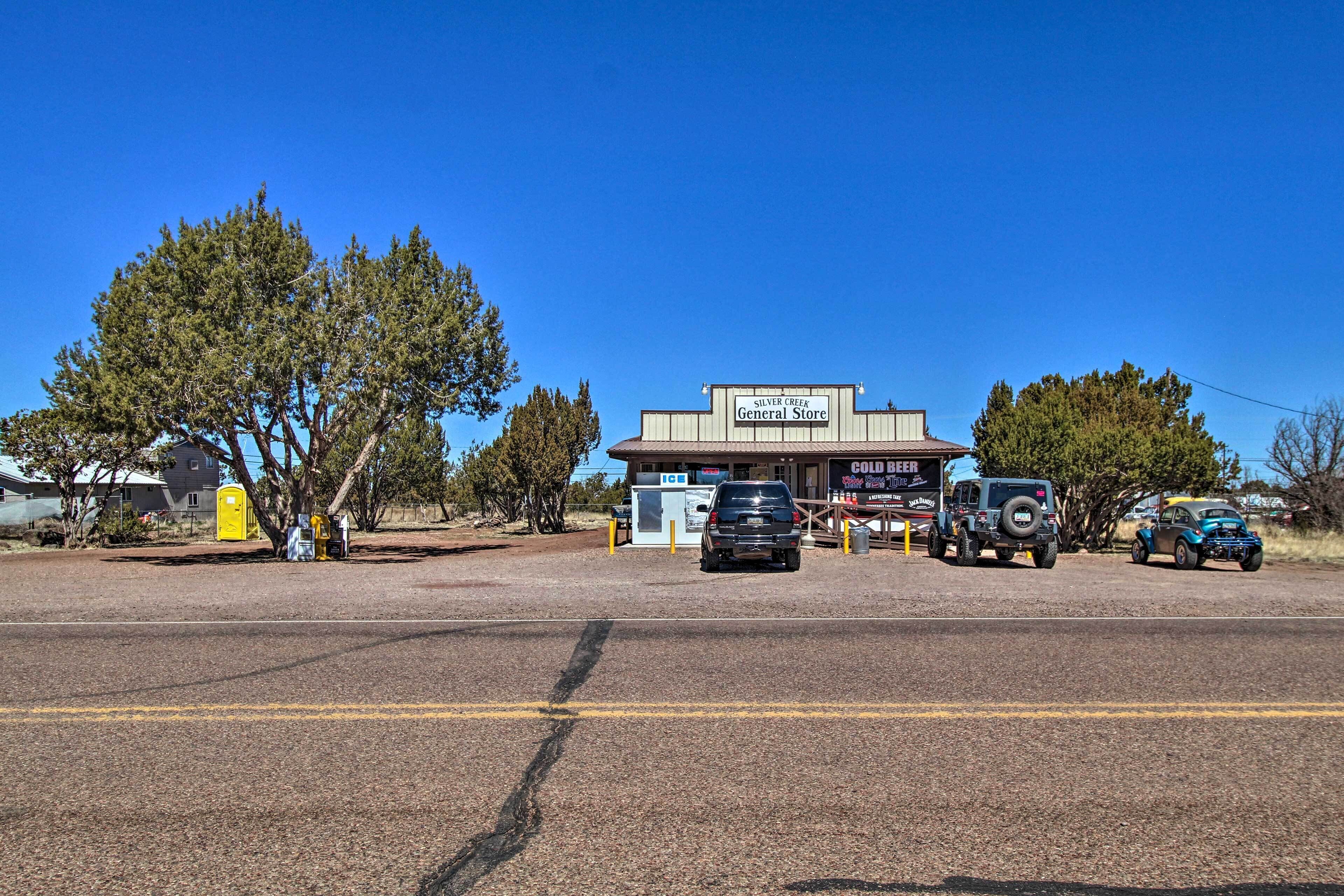 A general store with a signboard, a parking area with vehicles, and a clear blue sky.