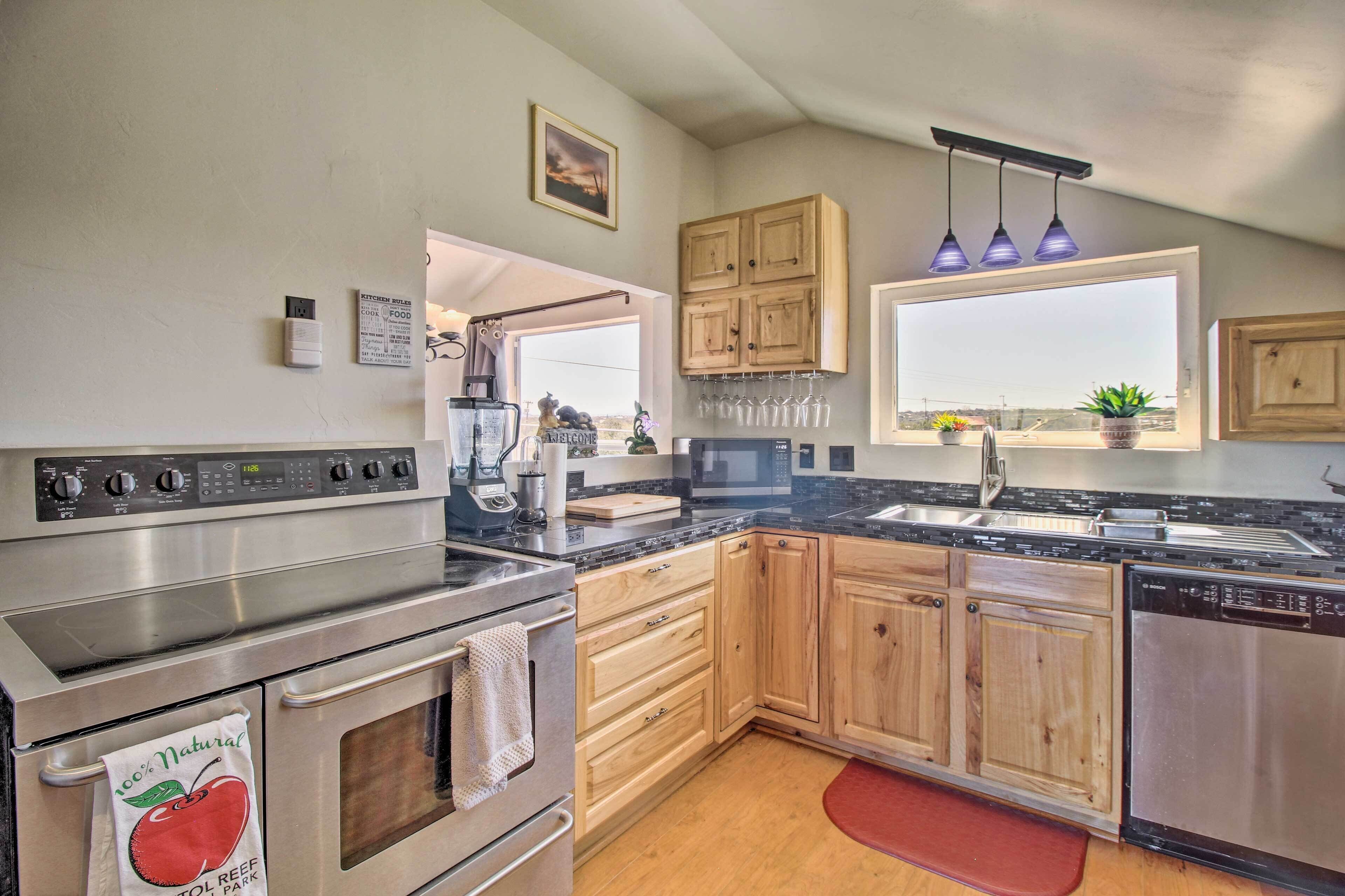 A kitchen with stainless steel appliances, wooden cabinets, a window with a view, and a kitchen rule sign.