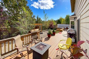 Une terrasse en bois avec des meubles d’extérieur, un foyer et des plantes en pot.