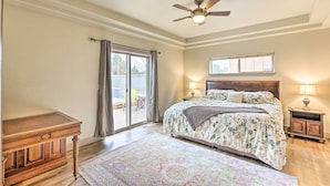 A bedroom with a bed, a ceiling fan, a nightstand, a dresser, and a large window. - Family-friendly Bend Home w/ Hot Tub & Yard! (Bend)