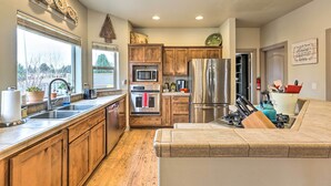 A modern kitchen with wooden cabinets, stainless steel appliances, and a built-in island with seating. - Family-friendly Bend Home w/ Hot Tub & Yard! (Bend)