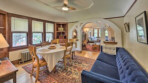A dining area with a table and chairs, a blue sofa, and a ceiling fan.
