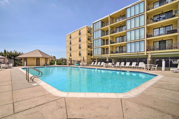 A swimming pool with lounge chairs and a building with balconies. - Family-friendly Brigantine Condo Near Beach! (Brigantine)