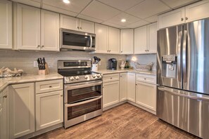 A modern kitchen with white cabinets, stainless steel appliances, a microwave, stove, oven, and refrigerator.