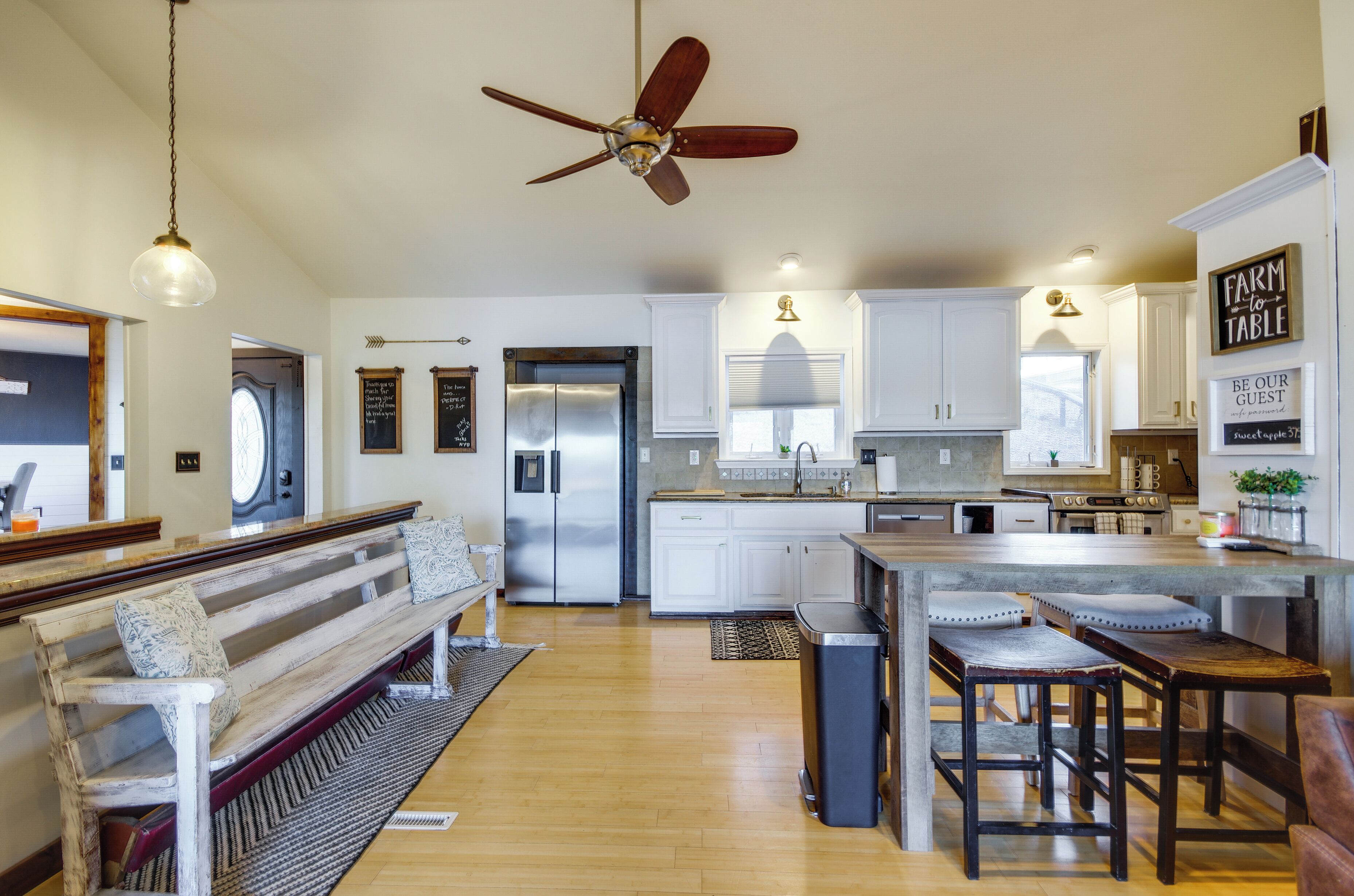A spacious kitchen with white cabinets, a central island, and a ceiling fan.