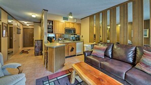 Una cocina moderna con armarios de madera, una isla central y una zona de comedor con sofá de cuero y mesa de madera.