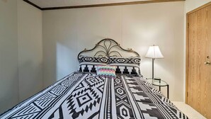 Un dormitorio con una cama, una mesita de noche, una lámpara y una puerta de madera.