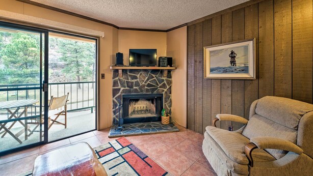 Una sala de estar acogedora con chimenea de piedra, un sillón cómodo, un televisor y un cuadro enmarcado en la pared.