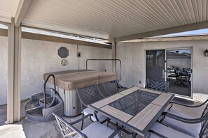 An outdoor patio with a table and chairs, a covered seating area, and a sliding glass door leading to an adjacent patio.